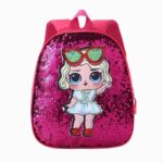 Cartable paillette avec design poupée. Le cartable est rose avec des sequins sur le devant et une poupée imprimée style dessins animés. Sur fond gris clair.