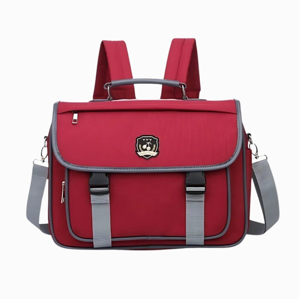 Cartable sac à dos style japonais de couleur bordeaux avec un détail style blason. Poignée, bretelles et bandoulière. Sur fond gris clair.