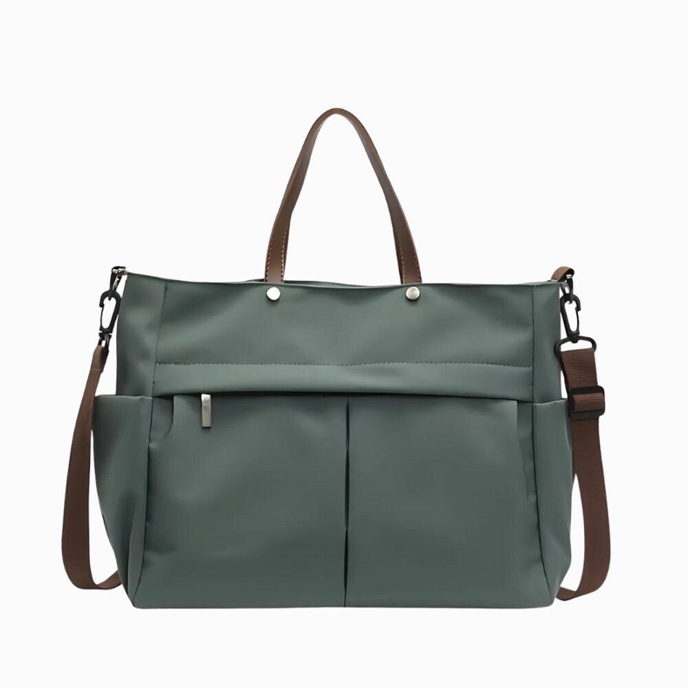 Cartable sac à main en nylon avec bandoulière pour femme de couleur verte avec une bandoulière marron et des anses en cuir synthétique marron. Une poche zippée sur le devant. Sur fond gris clair.