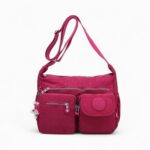 cartable besace rose foncé, bandoulière réglable large, nombreuses poches visibles, fond blanc