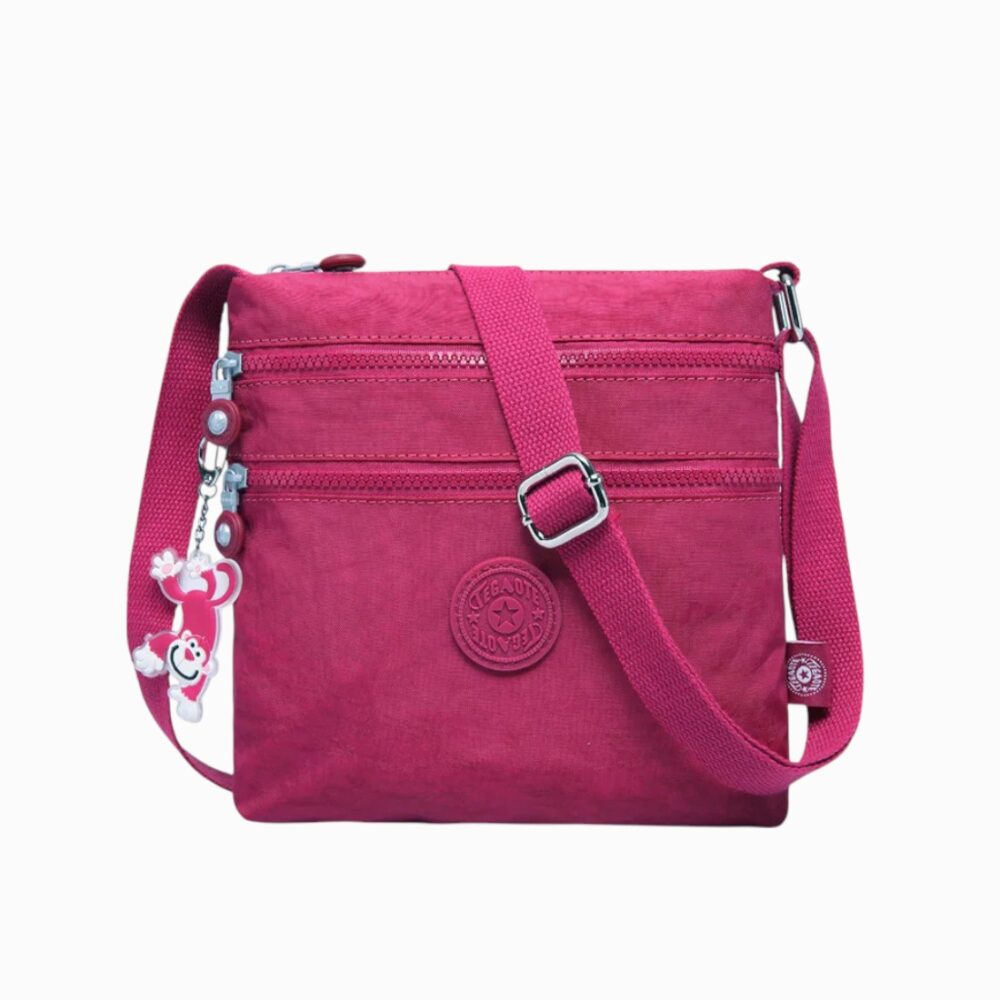 cartable rose foncé compact avec bandoulière réglable, pendentif fantaisie sur le zip, sur fond blanc