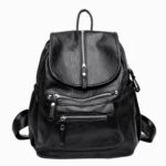 Cartable sac à dos en cuir véritable pour femme de couleur noire avec deux poches zippées devant. Sur fons gris clair.