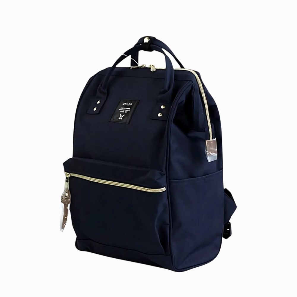 Cartable sac à dos pour femme avec ouverture large de couleur bleu marine. Les fermetures zippées sont dorées. Une poche frontale. Sur fond gris clair.