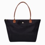 Cartable sac à main minimaliste pour femme de couleur noir avec des longues anses marron. Sur fond gris clair.
