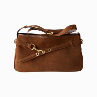 cartable en daim marron suspendu à une poignée de porte, avec anse épaule et boucle dorée, sur fond blanc