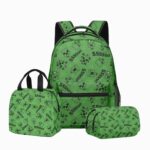 Un cartable Minecraft vert avec trousse et sac repas, imprimé de petits motifs carrés noirs, posé avec sa trousse et son sac repas assortis sur fond blanc.