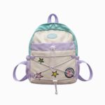 Un cartable Toy Story pour maternelle aux couleurs de Buzz l’Eclair, avec bretelles violettes, étoiles colorées et cordons sur le devant, posé sur fond blanc.