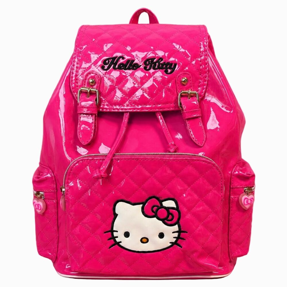 Un cartable Hello Kitty en cuir vegan vernis rose vif, avec face matelassée, logo Hello Kitty et poches à l’avant, posé sur fond blanc.